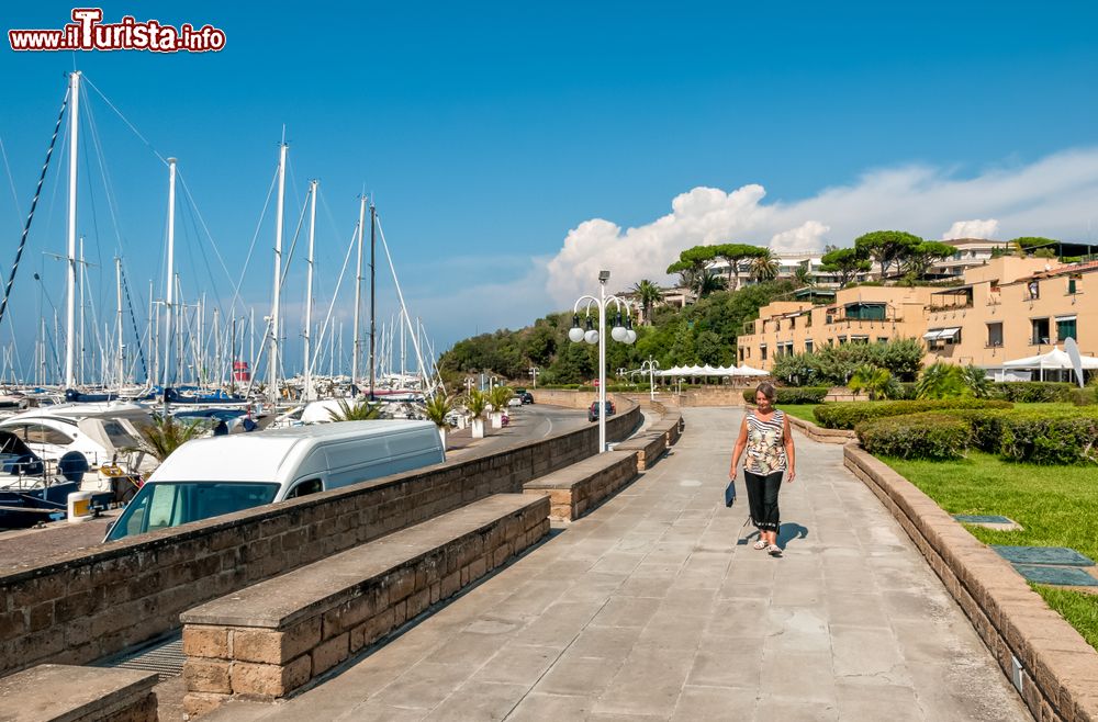 Immagine Uno scorcio di Punta Ala, Toscana, con una donna che passeggia lungo il porto.