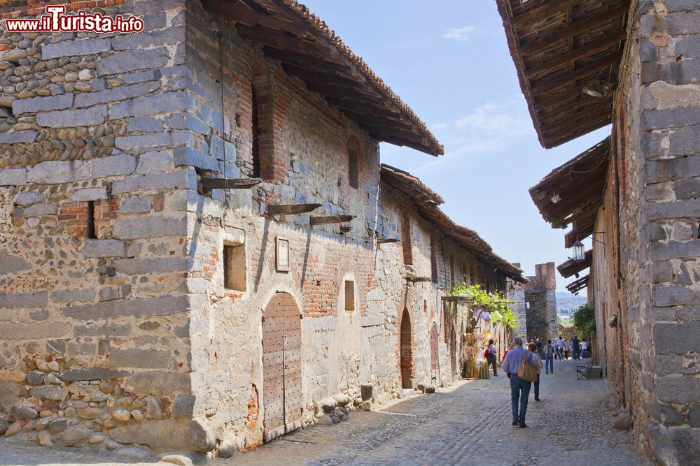 Immagine Uno scorcio fotografico di Ricetto di Candelo, Biella, Piemonte. Turisti in visita al borgo passeggiano per le vie dai grandi ciottoli inclinati.