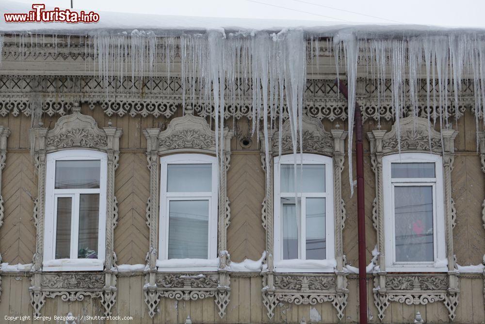 Immagine Una vecchia abitazione in legno con finestre decorate, tipica di Tomsk, durante il periodo invernale - © Sergey Bezgodov / Shutterstock.com