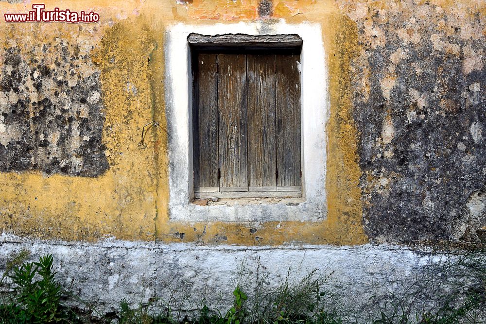 Immagine Un vecchio muro color giallo senape con persione in legno in un'abitazione di Othoni, Grecia.