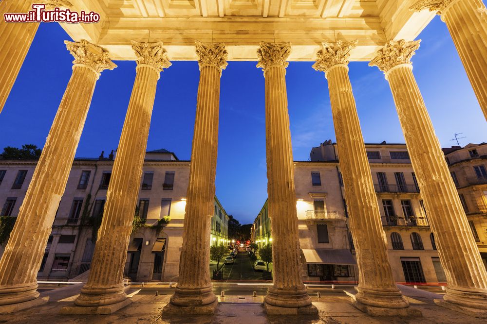 Immagine Veduta by night del centro di Nimes attarverso le colonne della Maison Carrée di Nimes, Francia.