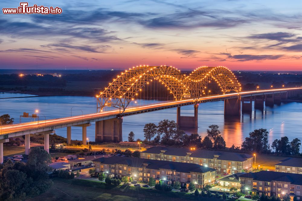 Immagine Veduta by night dell'Hernando de Soto Bridge, Memphis (Tennessee). Questo ponte ad arco è realizzato in acciaio e si presenta con una struttura sospesa a sbalzo. Di notte viene illuminato da 200 lampade al vapore di sodio lungo la lettera M.