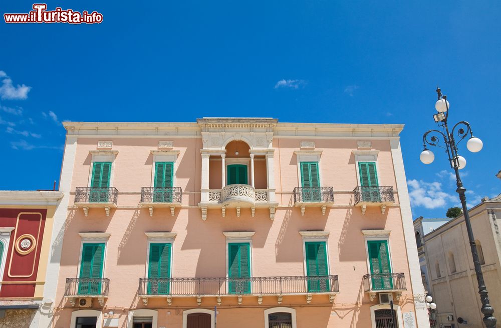 Immagine Veduta della facciata del Palazzo Latorre a Fasano, Puglia. Il rosa antico scelto per l'esterno è impreziosito dal verde degli scuri.