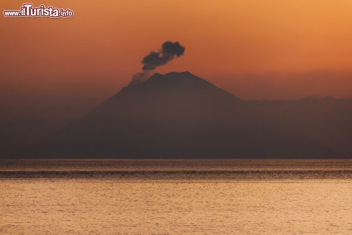 Immagine Veduta dello Stromboli da Salina, Sicilia - Una suggestiva immagine ritrae il vulcano durante un'eruzione all'alba. Lo Stromboli viene chiamato dai suoi abitanti "Struognoli" o "Iddu" in riferimento alla natura divina un tempo attribuita a fenomeni naturali non controllabili © andyparker72 / Shutterstock.com