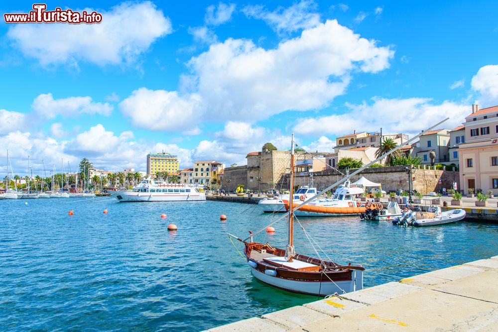 Immagine Veduta di Alghero e del suo litorale, Sardegna. Questa cittadina sarda è una delle località più amate dai turisti per via delle suggestive passeggiate lungo i bastioni del porto, i tetti rossi che sembrano toccare il cielo e l'insenatura naturale affacciata sul mare smeraldo.