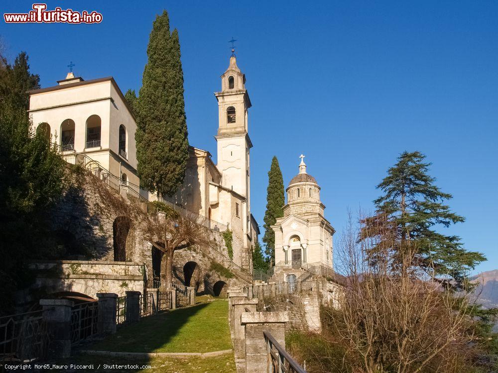 Immagine Veduta del villaggio con edifici religiosi lungo la costa ovest del lago di Como, Lombardia. Il paese con la sua bella architettura si incastra alla perfezione nel paesaggio naturale che lo circonda. In questa immagine le chiese sono fotografate in una giornata soleggiata e con il cielo blu - © Mor65_Mauro Piccardi / Shutterstock.com