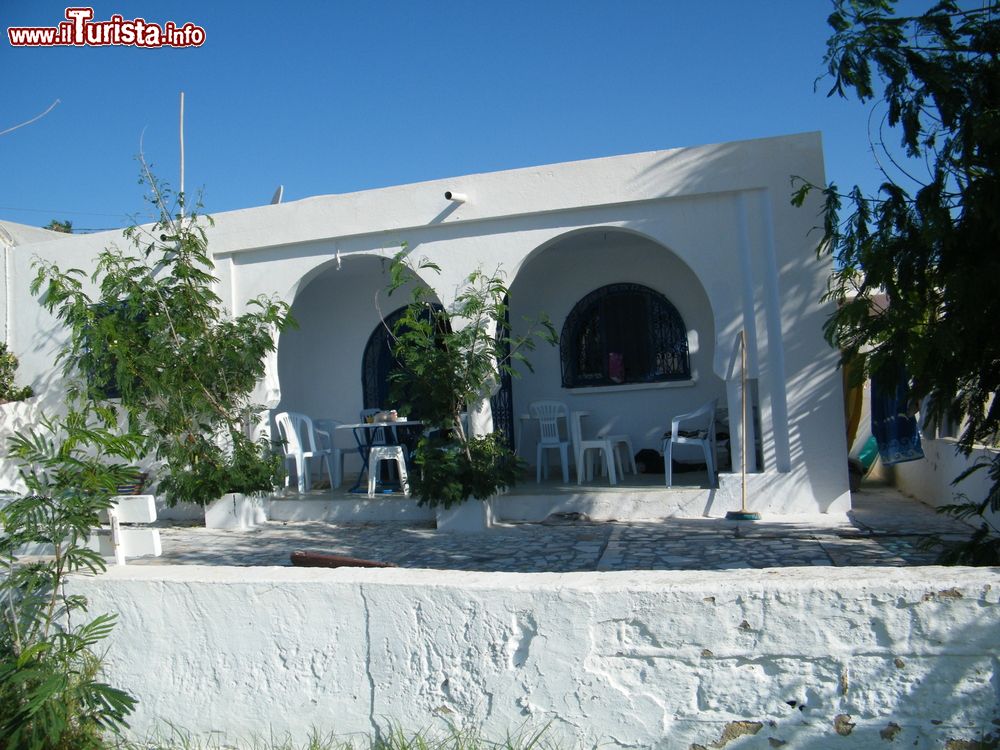 Immagine Veduta di una casa estiva a Maamoura, nei pressi di Nabeul, Tunisia. A fare da cornice al bianco dell'intonaco sono l'azzurro di porte e finestre e il verde della vegetazione.