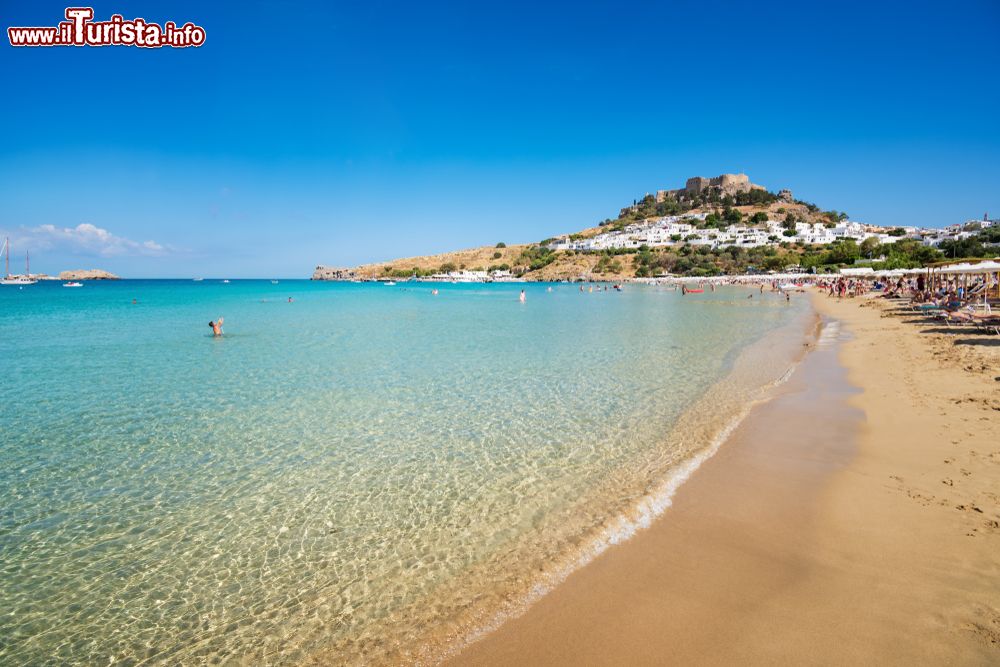 Immagine Veduta di una spiaggia sabbiosa nella Baia di Lindos, Rodi, con l'acropoli sullo sfondo (Dodecaneso). E' uno dei tratti di litorale più suggestivo di tutta la Grecia dove rilassarsi e nuotare nel mare cristallino.