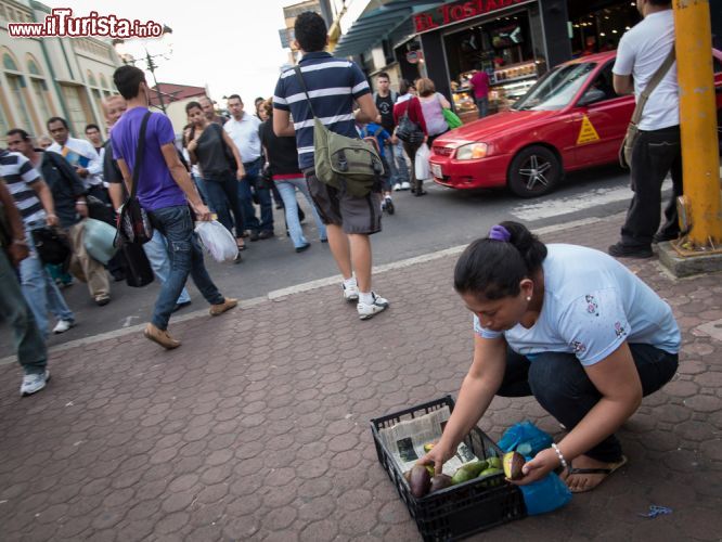 Immagine Venditore di strada in Avenida Central a San José, Costa Rica. Una donna di San José vende frutta lungo una delle strade più popolari della città. La capitale del Costa Rica è una delle destinazioni turistiche più visitate del paese con circa 2 milioni e 200 mila stranieri ogni anno - © Daniel Korzeniewski / Shutterstock.com