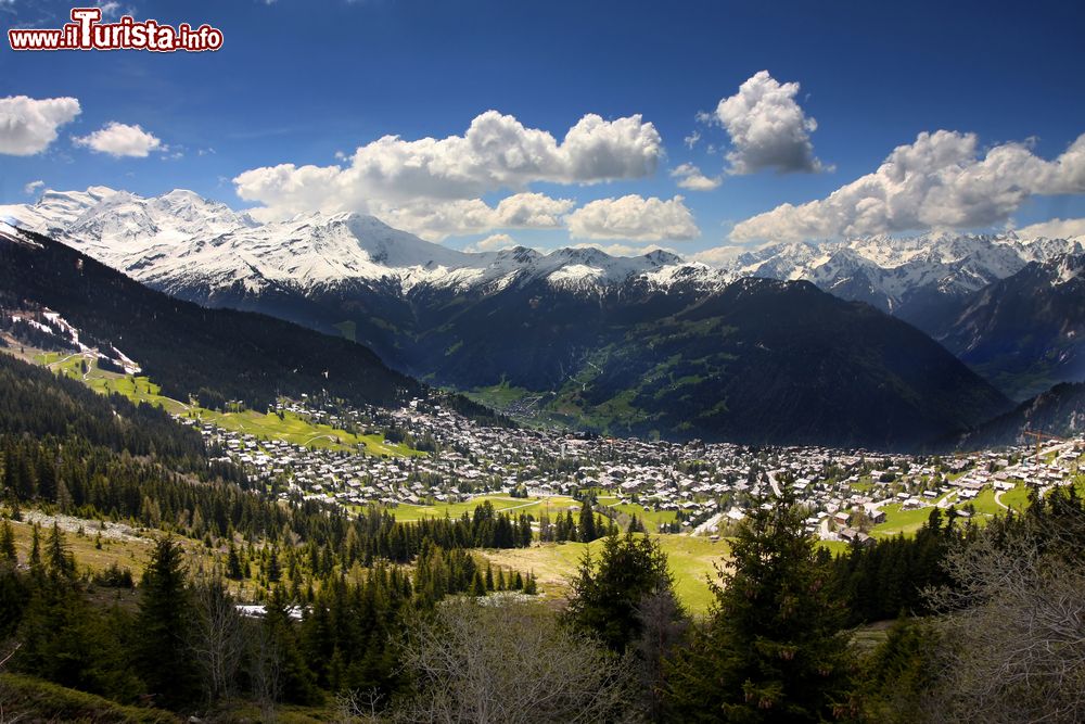 Immagine Verbier illuminata dal sole sotto un cielo azzurro e con le vette ricoperte di neve a fare da cornice, Svizzera.