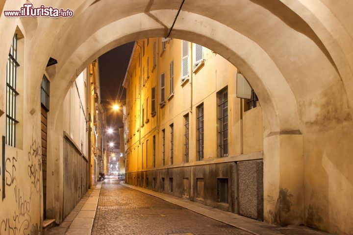 Immagine Veduta notturna di una delle vie storiche della città di Parma - è calata la notte su Borgo Bruno Longhi e il maestoso arco apre al centro storico di questa città dichiarata patrimonio dell'umanità dall'UNESCO. L'antichità del prestigioso centro storico appare ancora più imponente se posta in contrasto con le luci e i chiari segni della modernità. - © iryna1 / Shutterstock.com