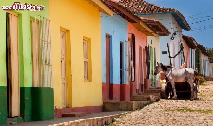 Immagine Le strade di Trinidad, Cuba - passeggiare per le stradine del centro di Trinidad è come fare un pittoresco salto indietro nel tempo, un salto all'era del colonialismo spagnolo nei Caraibi e, nonostante i tempi moderni del mondo, qui si possono ancora osservare le stradine in pietra, le case colorate, le auto d'epoca e tante cose che erano parte della quotidiana vita di campagna di un tempo. - © hagit berkovich / Shutterstock.com