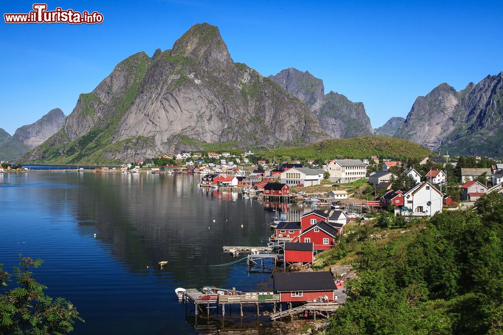 Immagine Uno splendido villaggio adagiato su un fiordo, Norvegia. Le casette in legno dipinte di rosso con il tetto nero si rispecchiano nelle acque azzurre e salate dei fiordi.