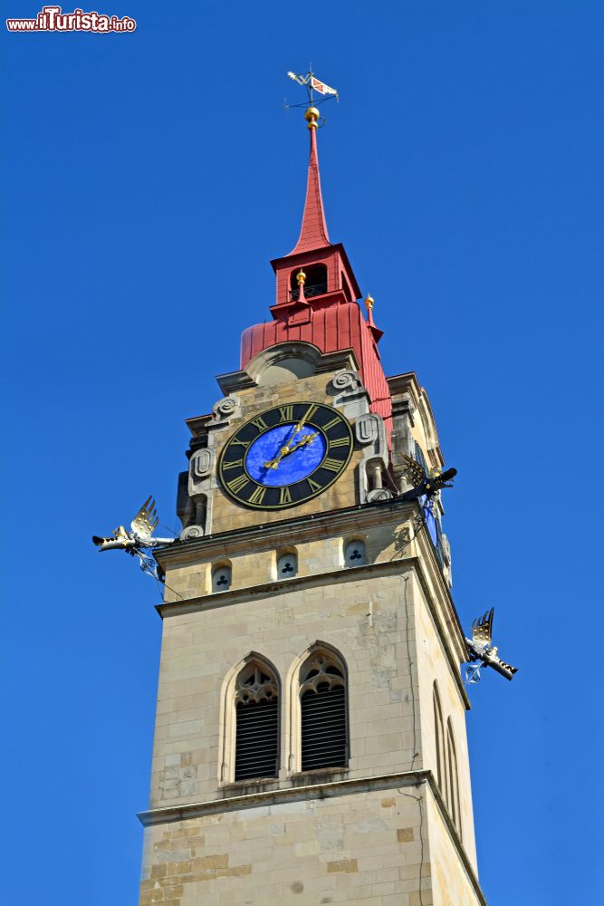 Immagine Vista di una delle torri gemelle colorate della chiesa principale di Winterthur, Svizzera. Si presenta con la guglia rossa e il disco dell'orologio dipinto di blu.