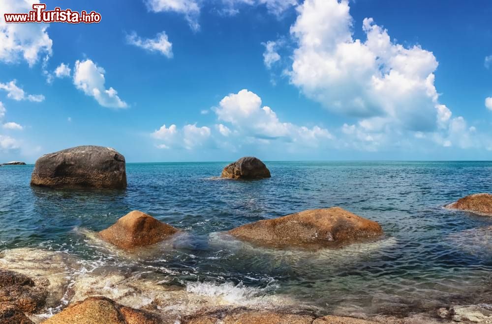 Immagine Vista panoramica della spiaggia di Chaloklum a Koh Pha Ngan, sud della Thailandia. Le acque dell'oceano lambiscono questa lunga striscia di sabbia bianchissima incastonata in una grande baia al cui centro si trova un villaggio di pescatori.