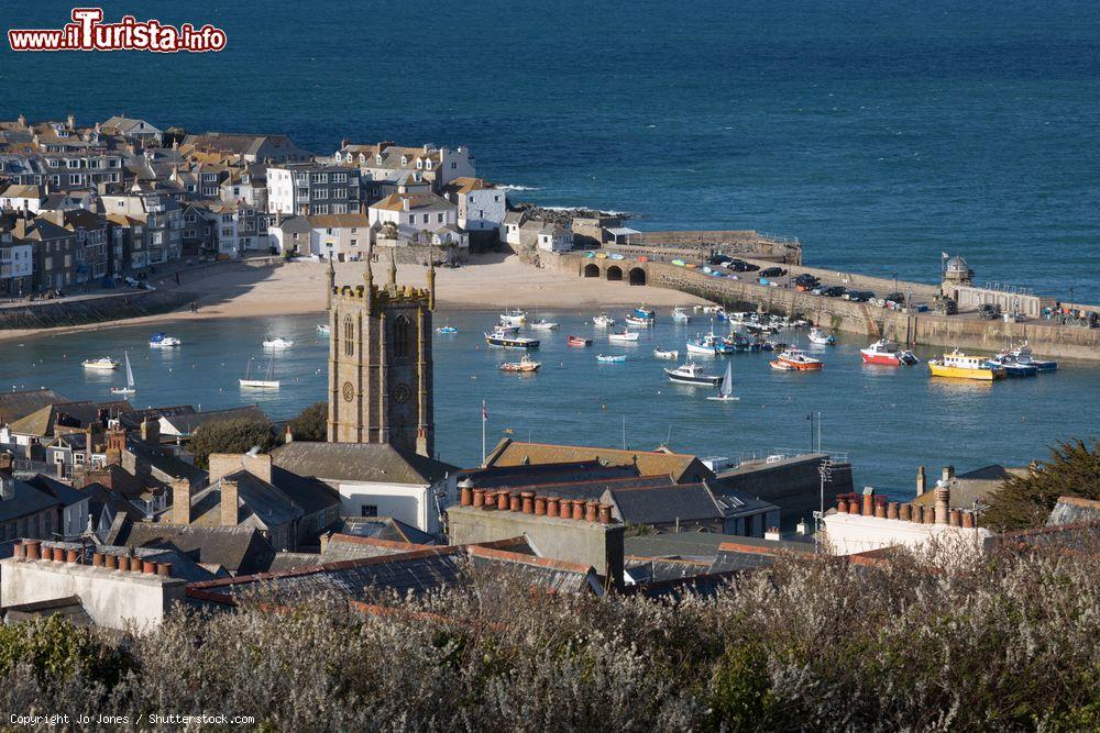 Immagine Vista sulla città vecchia e sul porto con le barche ancorate durante l'alta marea a St. Ives, Cornovaglia, Regno Unito. In primo piano la chiesa in un soleggiato pomeriggio di primavera - © Jo Jones / Shutterstock.com