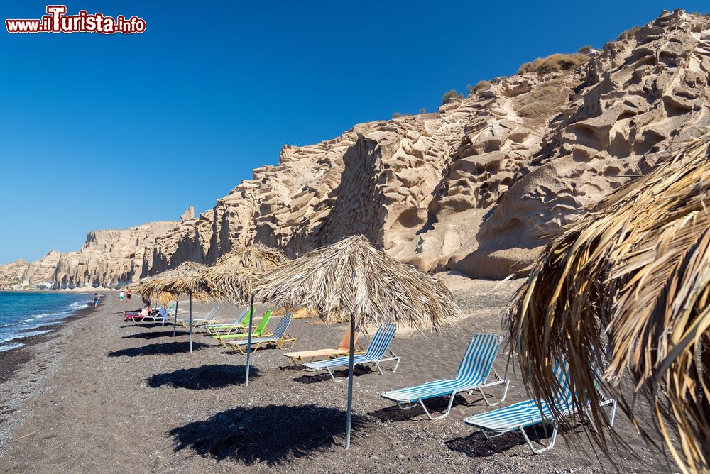 Immagine Vlychada beach, ombrelloni sulla spiaggia nera di Santorini, Grecia. Qui, a sud dell'isola di Santorini, a 14 chilometri da Fira, sembra di essere sulla luna. A renderla unica è la sabbia bianca mescolata a pietra di pomice con le scogliere rocciose che la proteggono dai venti.