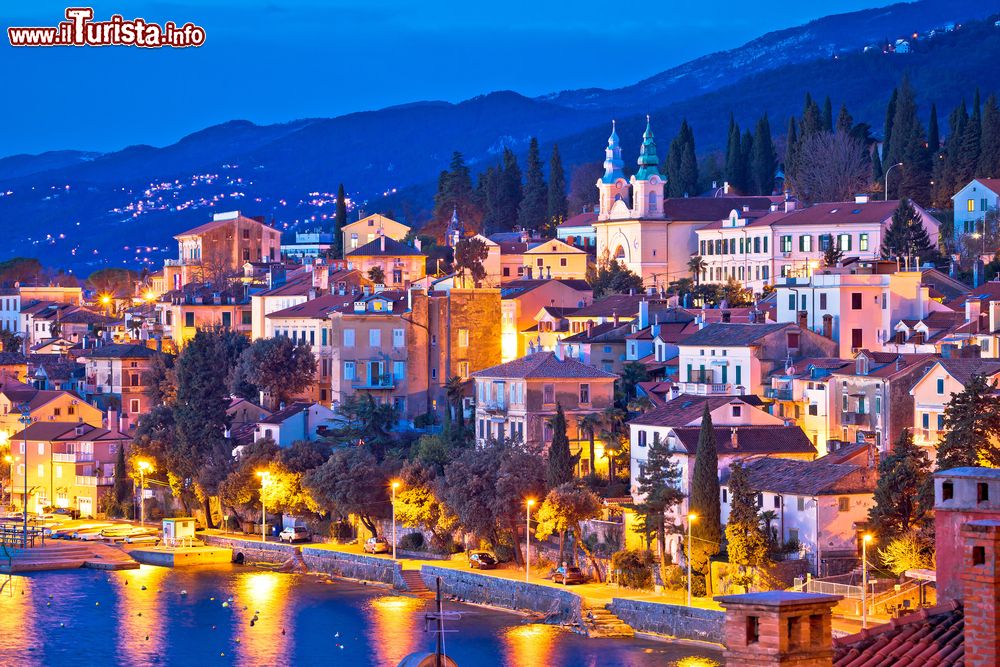 Immagine Volosko, nella Riviera di Opatija (Croazia), fotografata alla sera con le luci accese che si riflettono sull'acqua.