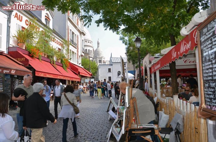 Immagine Parigi golosa: ristoranti e locali lungo una strada di Montmartre, sullo sfondo la Basilica del Sacro-Cuore - © wjarek / Shutterstock.com
