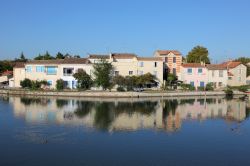 Canale e tipiche case della Camargue nei pressi di Aigues Mortes, Francia - Si riflettono sulle acque del canale le graziose e caratteristiche abitazioni della Camargue che rendono ancora più ...