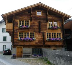 Chalet in legno con gerani in centro ad Andermatt (Svizzera)