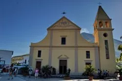 Chiesa San Vincenzo a Stromboli, Eolie. Sullo sfondo il vulcano con del fumo.