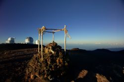 Isola di Hawaii, cima del vulcano Mauna Kea: il contrasto tra l'arcaico e il moderno. In primo piano un tipico Heiau, tempio sacro hawaiano. Templi come questo potevano essere costruiti ...