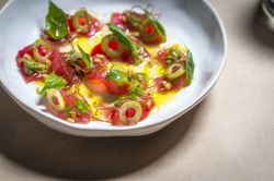 Un piatto di tonno crudo con olive e pomodori in un ristorante di New York, USA - © Noah Fecks