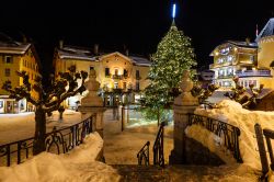 Albero di Natale nella piazza innevata di Megève (Alta Savoia) illuminato di sera, Francia.

