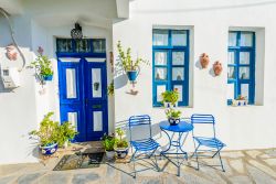 Architettura greca nel villaggio di Mandraki, Grecia, con finestre e porte blu e muri bianchi.

