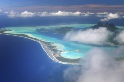 L'atollo di Bora Bora (Isole della Società, Polinesia Francese) visto dall'alto in una giornata di nuvole. La stagione delle piogge va da novembre a aprile: le temperature sono ...