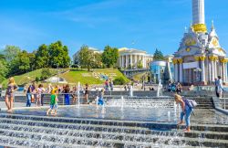 Bambini giocano nella fontana di Maidan Nezalezhnosti a Kiev, Ucraina. Independence Square ospita questa bella fontana con l'orologio di fiori e il palazzo Ottobre sullo sfondo - © ...