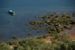 Barca da pesca ormeggiata nel lago a Cacela Velha, nel sud del Portogallo -  Ancorata fra le acque blu intenso di questo piccolo lago nei pressi di Cacela Velha, una barca ricorda che un ...