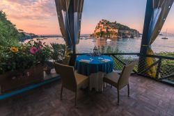 Cena romantica al tramonto su una terrazza di Ischia, con vista sul Castello Aragonese.