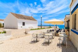 Chiesa e ristoranti sulla passeggiata costiera nella città di mare di Armacao de Pera, Portogallo. Per secoli questa è stata una località di pescatori attirati dall'abbandonza ...