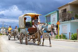 Cubani su carri trainati da cavalli in una strada di Holguin, Cuba. L'isola ha il più basso numero di veicoli pro capite al mondo - © alexsvirid / Shutterstock.com