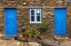 Dettaglio di una vecchia casa in pietra a Piodao, Portogallo - La roccia con cui sono costruite le case di Piodao incornicia le belle porte azzurre tipiche di tutte le abitazioni di questo villaggio ...