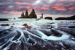 Formazioni di basalto di fronte alla spiaggia nera di Reynisdrangar, Vik i Myrdal, Islanda. A fare da cornice, uno splendido cielo con i colori del tramonto.
