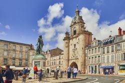 Gente a passeggio nella vecchia cittadina di La Rochelle, Francia. Sulla destra, la porta del grande orologio costruita in mattoni - © Nevskii Dmitrii / Shutterstock.com