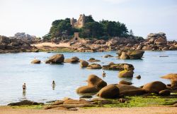 Gente in spiaggia a Ploumanac'h, Bretagna (Francia). Sullo sfondo, un castello della Costa di Grantio Rosa affacciata sulla Manica 