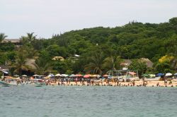 Gente sulla spiaggia di Puerto Escondido, Messico. Sullo sfondo, la lussureggiante vegetazione di questa località balneare e turistica.

