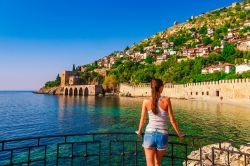 Una giovane donna ammira l'antico cantiere navale di Alanya, Turchia, dalla torre di Kizil Kule. Siamo nel distretto di Antalya: la torre di Kizil Kule è considerata il simbolo della ...
