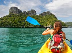 Una giovane donna fa kayak nel parco nazionale marino di Ang Thong, Thailandia.

