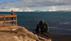 Turista sulla terrazza panoramica davanti al Hvitserkur, il celebre faraglione di basalto lungo la costa della penisola di Vatnsnes, non distante da Hvammstangi (Islanda).
