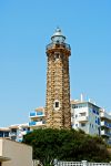 Il faro di Estepona con edifici e palazzi sullo sfondo, provincia di Malaga, Spagna. Si trova a Punta Doncella e risale agli anni '20 del 1900. Attorno ci sono giardini con aiuole e una ...