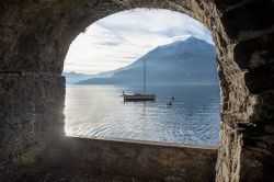Il lago di Como visto da Varenna, Lombardia. Atmosfera suggestiva per uno scorcio fotografico del Lario ritratto attraverso uno degli edifici storici del villaggio di Varenna - © COLOMBO ...