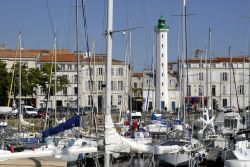 Il porto della città di La Rochelle, Francia. Sullo sfondo, dietro le barche ormeggiate, il faro bianco e verde.



