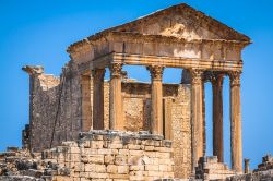 La facciata del Tempio Capitolino di Dougga, Tunisia. Si tratta di una costruzione con colonne a fusti scanalati sormontati da capitelli in stile corinzio.

