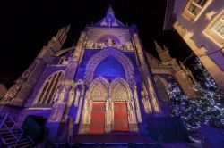 La facciata della chiesa di San Teobaldo decorata per Natale e illuminata di notte, Alsazia, Francia.

