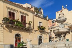 La fontana di Piazza Duomo con edifici e balconi fioriti sullo sfondo, Taormina. Un caratteristico scorcio fotografico nel cuore della città siciliana.


